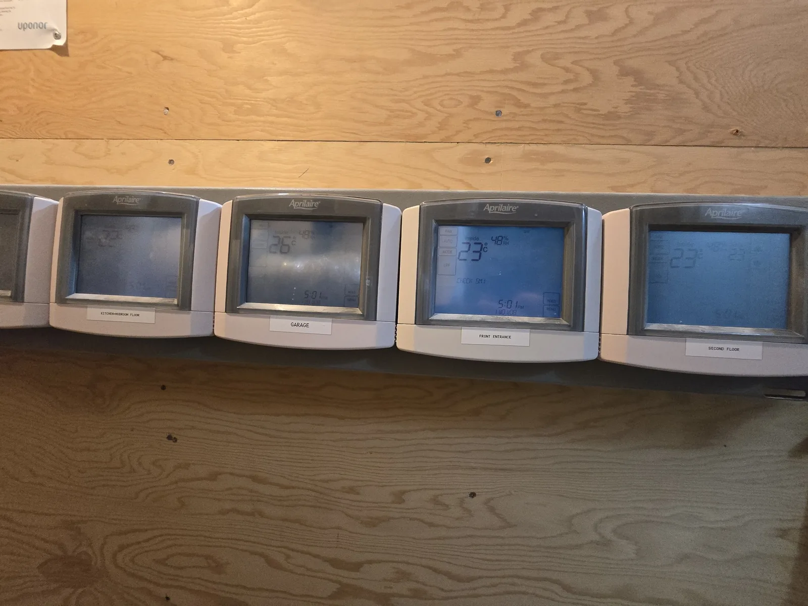 A bank of Aprilaire zone thermostats installed by KeenAI, each hand-labelled for garage, front entrance, second floor and kitchen-mudroom floor
