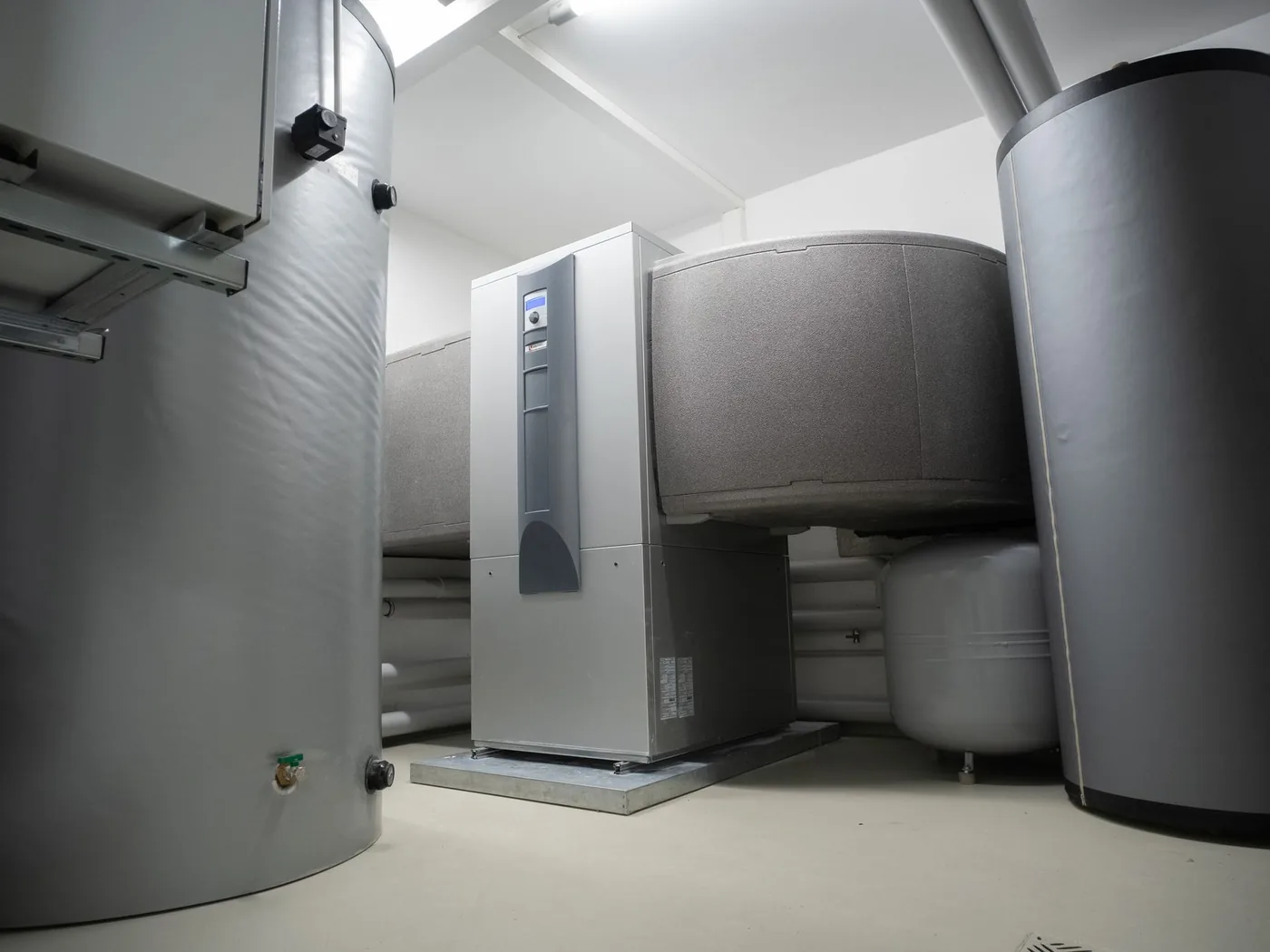 A domestic mechanical room containing insulated buffer tanks, an expansion vessel and a floor-standing heating unit